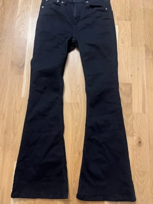 Svarta utsvängda jeans - Säljer ett par svarta jeans med utsvängda ben och klassisk femficksmodell. Jeansen har hög midja och är tillverkade i ett mjukt denimtyg som ger en snygg siluett. Perfekta för dig som gillar retrostil och vill sticka ut lite extra.Jag har använt 1 gång de är jättenya.Pris kan diskuteras 