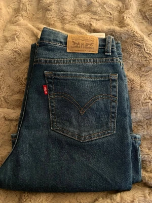 Blå bootcut jeans från Levi's - Säljer ett par klassiska blå bootcut jeans från Levi's med deras röda logga på bakfickan. Jeansen är normala i midjan midja. Nypris köpte för ca 1000 kr o säljer för 300. Passar s/xs
