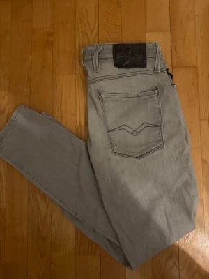 Replay Anbass jeans – 31/30 slim fit - Säljer dessa snygga ljusgrå Replay Anbass jeans i Slim Fit, storlek W31 L30 Jeansens har snygga slitningar som ger dem en trendig och stilren look. I bra använt skick.  Om du har några frågor tveka inte att höra av dig. Allt gott Deluxe Garderoben