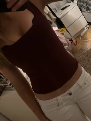 Vinröd linnetopp från Gina Tricot - Vinröd, tight och croppad linnetopp från Gina Tricot med smala axelband. Enkel och stilren design som passar perfekt till jeans eller kjol. Tillverkad i mjukt material som sitter skönt mot kroppen.