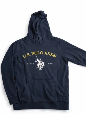 Marinblå hoodie från U.S. Polo Assn - Snygg marinblå hoodie från U.S. Polo Assn med gul och vit liga. Klassisk skön huva. Perfekt med de jeansen som ligger ute för en skön stil. Vid frågor är det bara att skriva:)