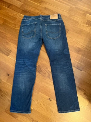 Mörkblå Jack and Jones jeans i straight fit - Säljer ett par mörkblå jeans med rak passform och klassiska fem fickor. Jeansen har en snygg tvätt och kontrastsömmar. Perfekta till vardags och passar till det mesta. Säljer för 179kr men pris går att diskuteras. Storleken är W32 L30.