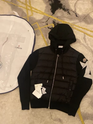 Mocnler cardigan  - Snygg svart hoodie från Moncler med vadderad front och stickade ärmar. Kommer med originala förpackning inga skador eller fläck nästan som ett helt ny, scan, kan gå ner lite i pris vid snabb affär! 
