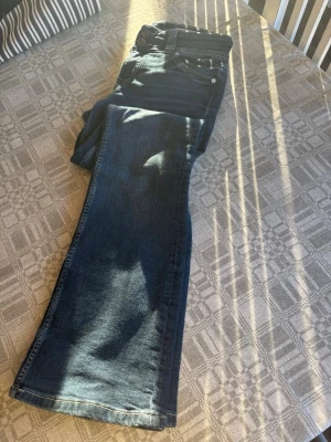 Mörkblå bootcut jeans - Säljer ett par mörkblå bootcut jeans från Bershka i storlek 36, dom har lite slitningar på benen (se sista bilden) och ena knappen på bakfickan är lite lös men tror det går att fixa💕