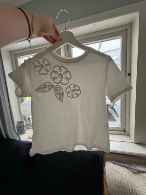 Vit t-shirt med broderade blommor - Skitsnygg basic tshirt med blomdetaljer, passar till allt🥰 Säljer då den tyvärr lite för liten för mig. 