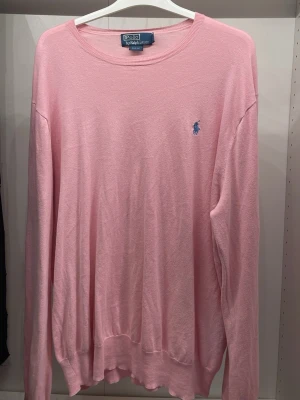 Rosa tröja från Polo Ralph Lauren - Snygg rosa långärmad tröja från Polo Ralph Lauren i slim fit-modell. Tröjan har rund halsringning och den klassiska blå logotypen broderad på bröstet. Perfekt för dig som gillar stilrena och tidlösa plagg.