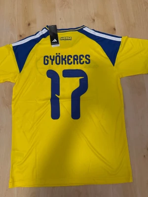 Gyökeres #17 – Sverige Hemma (storlek M) - Gyökeres #17-tryck. Sverige Hemma (gul). Storlek M. Helt ny och aldrig använd. Skickas snabbt 🚚💨  Mått (M): Halvt bröstmått 53 cm • Längd 74 cm • Ärmbredd 23 cm • Axelbredd 44 cm • Ärmlängd 40 cm • Manschett 19 cm.  🔥 Fan Edition – normal passform. 🇸🇪 Sverige landslag.  📩 Skicka gärna ett meddelande vid frågor eller prisförslag! 🛍 Bundle-rabatt upp till 20%! 📦 Skickas samma eller nästa dag.