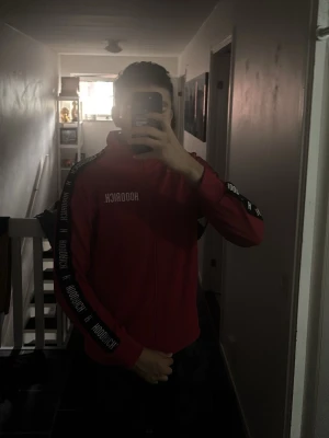 Röd hoodie från Hoodrich med tryck - Säljer en röd hoodie från Hoodrich med vit logga på bröstet och text längs ärmarna. Hoodien har dragkedja, huva och svarta detaljer på ärmarna. Perfekt för dig som gillar streetwear och vill sticka ut. Köptes för 1250kr men säljer för endast 350kr