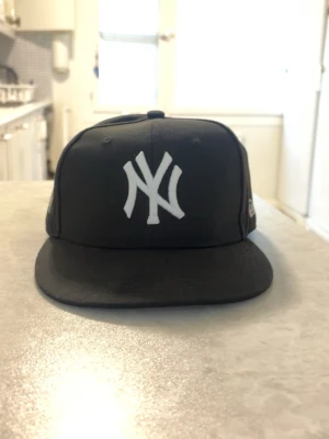 New Era MLB Yankees fitted keps  - Svart Yankee MLB keps från New Era med World Series tryck på sidan i fitted modell. Storleken är 7 1/2. 