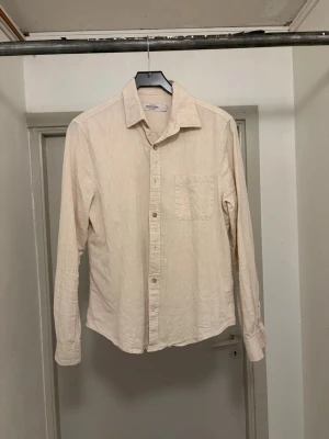 Beige linneskjorta Dressman - Säljer en stilren beige skjorta i linne från Dressman. Skjortan har långa ärmar och knäppning framtill. Perfekt för dig som gillar en enkel och clean look. Nypris 599kr. Kan gå ner i pris vid en snabb affär!