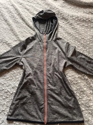 Grått träningsset med hoodie och tights - Säljer ett gråmelerat träningsset från H&M som består av en långärmad hoodie med dragkedja och fickor samt matchande tights med svart midjeresår. Perfekt för träning och vardag. Materialet är stretchigt och den sitter som en XS-S.