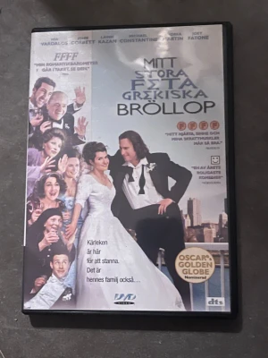 Mitt stora feta grekiska bröllop DVD - DVD-film med titeln 'Mitt stora feta grekiska bröllop'. Omslaget är färgglatt med bilder på huvudkaraktärerna i bröllopskläder och flera familjemedlemmar. Filmen är en romantisk komedi och omslaget har svensk text. DVD-fodral i plast.