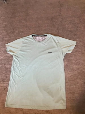 Ljusgrön t-shirt från BOSS - Snygg ljusgrön tunnare t-shirt från BOSS med diskret logga broderad på bröstet. Klassisk rund halsringning och korta ärmar. Perfekt för en clean och stilren look.