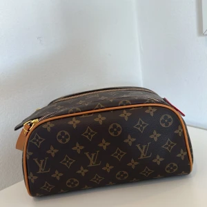 Brun trendig necessär med monogram mönster Snygg och klassisk  - Säljer en klassisk necessär i monogram mönster som är både snygg, populär och trendig. Den har två dragkedjor upptill och guldfärgade metalldetaljer. Perfekt för att organisera dina hygienartiklar, smink, och småsaker i vardagen och på resan. Den är både rymlig och praktisk. 