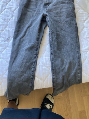 Grå raka jeans - Säljer ett par grå jeans med rak passform och klassisk femficksdesign. Jeansen har en enkel look utan synliga loggor eller detaljer och är tillverkade i ett mjukt denimtyg. Perfekta för en avslappnad och stilren outfit.