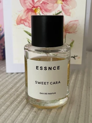 ESSNCE Sweet Cara - ESSNCE Sweet Cara Eau de Parfum i en stilren, rund glasflaska med svart lock. Doften är inspirerad av Cheirosa 62 från Sol de Janeiro.  Perfekt för dig som gillar somriga och söta dofter med noter av pistasch och caramel. 