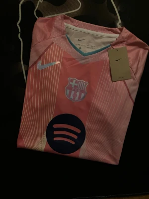 Rosa FC Barcelona Nike - Säljer en rosa FC Barcelona matchtröja från Nike med vita och ljusblå detaljer. Tröjan har klubbmärke, Nike-logga och Spotify-logga på bröstet. Tillverkad i Dri-FIT-material som andas, perfekt för träning eller match. Står M-Passar S-XS Helt ny, diskuterar ej pris.-frågor funkar 100% 