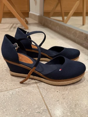 Mörkblå sandaletter - Mörkblåa sandaletter med stängd tå från Tommy Hilfiger. Mycket fint skick. Använda ett fåtal gånger och sen dess samlat damm i garderoben. Säljs i befintligt skick. 