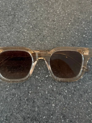 Transparenta fyrkantiga solglasögon - Snygga solglasögon med transparent beige båge och fyrkantig form. Glasen är mörka och ger en cool kontrast till den ljusa ramen. Perfekta för soliga dagar och en trendig look. Låda och påse medföljer 