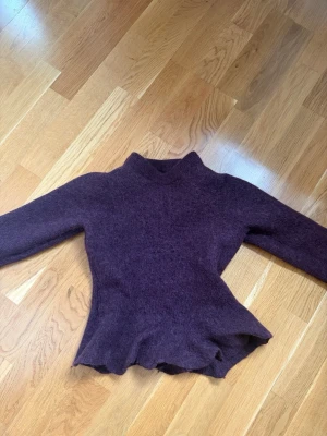 Vinröd stickad tröja Visual Clothing Project - Mysig vinröd stickad tröja från Visual Clothing Project. Tröjan har lång ärm och en lätt utsvängd midja som ger en snygg siluett. Materialet är fluffigt och mjukt, perfekt för kyligare dagar. Har krympt i tvätten så skulle säga att den passar xxs-xs 