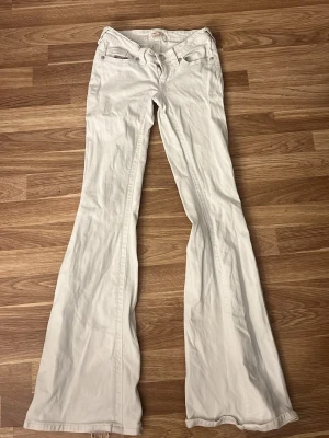 Vita bootcut jeans med låg midja - Dem är nytvättade de därför dem är skrynkliga! Säljer ett par vita bootcut jeans med låg midja och klassiska fickor fram och bak. Jeansen har vida ben och är perfekta för dig som gillar en retro vibe. Styla med en crop top eller hoodie för en chill look.använda fåtal gånger, 