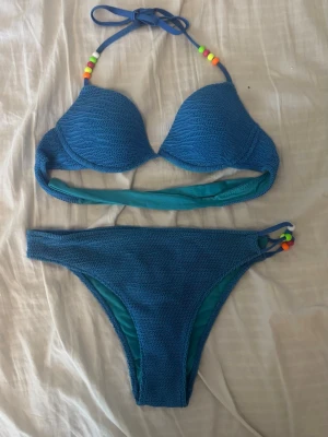 Blå bikini från CALZEDONIA - Säljer en blå bikini med färgglada pärlor på banden. 