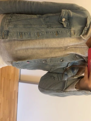 Ljusblå jeansjacka från &Denim - Snygg ljusblå jeansjacka från &Denim i klassisk modell med bröstfickor och silvriga knappar. Jackan har en avslappnad passform och är tillverkad i slitstarkt jeansmaterial. Perfekt att slänga över en hoodie eller t-shirt för en cool look.