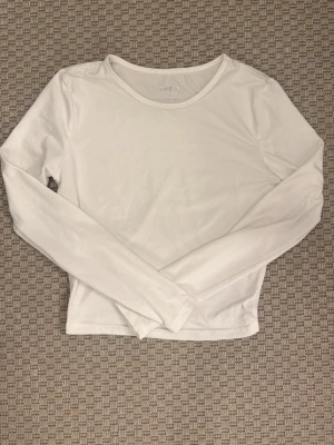 Vit långärmad topp från SHEIN - En enkel och stilren vit långärmad topp från SHEIN. Toppen har rund halsringning och är gjord i ett mjukt material som sitter bekvämt mot kroppen. Perfekt att matcha med jeans eller kjol för en clean look.