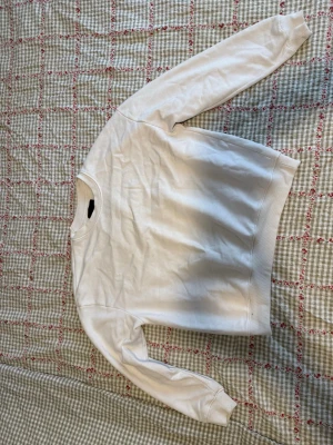 Vit sweatshirt från Lager 157, storlek M - En stilren vit sweatshirt från Lager 157 i storlek M. Tröjan har rund halsringning, ribbade muddar vid ärmslut och nederkant samt en klassisk passform. 