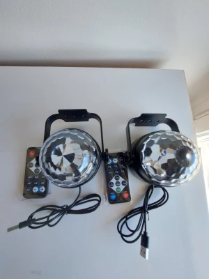 2-pack LED Party Lights med Fjärrkontroll - Höj stämningen på nästa fest eller förvandla barnrummet med detta set om två (2) LED RGB-discolampor! Dessa lampor skapar en färgstark ljusshow som täcker både tak och väggar med levande mönster. Egenskaper: 2-pack: Du får två separata enheter vilket gör det enkelt att täcka ett större rum eller använda i olika rum. Flera lägen: 7 olika färglägen  Fjärrkontroller: Varje lampa har en egen fjärrkontroll för att enkelt justera färg, hastighet och mönster. USB-driven: Kopplas smidigt in i valfr