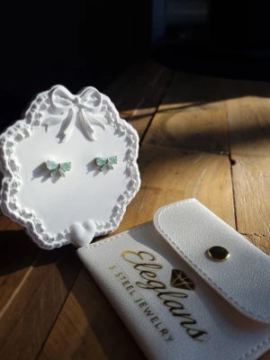 Mint Bow Earrings  - En tidlös elegans örhängen förenar en klassisk vintage-look med modern minimalism. Örhängen är prydda med ljusreflekterande kristaller i en förtrollande havsgrön nyans. Tillverkad i Korea.     Material: Rhodium , CZ-diamant Nickeltestat & allergivänligt                  Storlek: Längd ca 1,3cm Bredd ca 0.3cm -Inga prisförslag, tack.                                       - Varan packas noggrant och säkert 