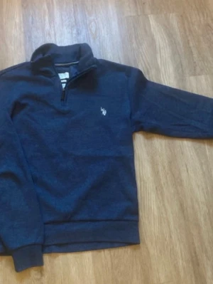 Mörkblå tröja med dragkedja Polo Ralph Lauren - Mörkblå långärmad tröja från Polo Ralph Lauren med halv dragkedja och ståkrage. Broderad logga på bröstet. Perfekt för lager-på-lager och enkel att matcha med jeans eller chinos.