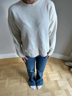 Vit oversized stickad tröja🌸💖💖 - En vit, oversized stickad tröja med rund halsringning och breda ribbade muddar vid ärmslut och nederkant. Tröjan har en avslappnad passform och är perfekt för lager-på-lager-stil. Enkel och stilren design som funkar till det mesta.