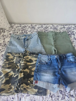 Fyra par shorts i olika stilar - Fyra par shorts: ett par ljusblå denimshorts, ett par gröna shorts, ett par camouflagemönstrade shorts och ett par blå jeansshorts med uppvik. Perfekta för sommaren och att mixa olika looks.