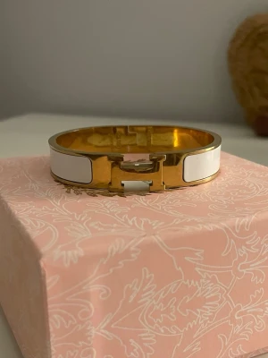 vit och guld Clic H armband - Snyggt Clic H armband i guldpläterad metall med vita emaljdetaljer. 