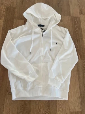 Vit hoodie från Polo Ralph Lauren - Snygg vit hoodie från Polo Ralph Lauren med dragkedja framtill. 