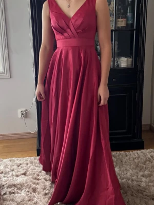 Ny balklänning. 34. xs. NWT JJ's House. Klänning - Elegant och vacker balklänning. Fin lyster och kvalitét på tyget, inte tunnt o sladdrigt. Sitter jättefint på och faller fint. Fin drapering över byst, och jättefin i ryggen. Dubbelt tyg i kjolen som har lite vidd och rör sig fint vid rörelse. Markerad midja. Dragkedja i ryggen. Färgen heter Cinnamon Rose. Storlek 34. XS. Min dotter på bilderna är 171 lång. Med klackar hade den blivit perfekt i längden. Köpt på JJs House. Lapparna kvar. Finns inget att anmärka på. NWT. 