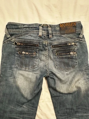 Morgan de Toi jeans – Y2K low rise - Snygga blå y2k jeans från Morgan med naturliga slitningar och coola detaljer som dragkedjor på bakfickorna. Jeansen har en klassisk femficksmodell, låg midja och smal passform. Tillverkade i denim med cool tvättad look och detaljer som ger en trendig vibe. Innerbenslängd: ca 75,5cm.
