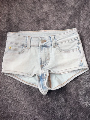 Ljusblå mini denimshorts från Cheap Monday - Säljer ett par ljusblå denimshorts från Cheap Monday med klassisk femficksdesign och råa kanter. Shortsen har en snygg patch med logga och döskalle bak. Perfekta för varma dagar och enkel att matcha med allt. Säljer pågrund av att dem inte passar mig.