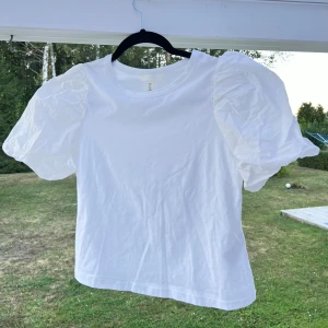 Vit t-shirt med puffärmar, stl M - Vit t-shirt med puffärmar 🥰 Är normalt storlek S så den är lite stor för mig. Den blev tyvärr bara liggandes i garderoben så därför väljer jag att sälja den istället 💕  (ALDRIG ANVÄND)  Längd: 50 cm Axel: 30 cm Byst: 76 cm