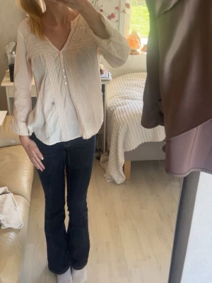 Ljusbeige blus med spets och knappar - Super söt Ljusbeige blus med dekorativa spetsdetaljer och knappar framtill. Blusen har långärmad design och v-ringad hals, samt fina plisserade partier på bröstet. Perfekt för dig som gillar en romantisk och avslappnad stil.🤍 knapparna på armen gör att man kan justera längden🤍🤍