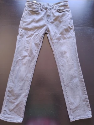 Grå Levi's jeans 511 32/32 med rak passform - Säljer ett par grå jeans från Levi's med klassisk rak passform i storlek 32/32. Jeansen har fem fickor, bälteshällor och dragkedjegylf. Tillverkade i bomullsdenim med en snygg tvättad look. Perfekta för en avslappnad och stilren outfit.