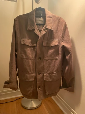 Brun overshirt från Dressman  - Snygg brun overshirt från Dressman  i ett mjukt linnematerial. Jackan har fyra stora fickor framtill, klassisk krage och knäppning med bruna knappar. Perfekt lager-på-lager-plagg med avslappnad passform och stilrena detaljer. Prefekt till våren 🔅