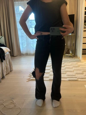 Svarta bootcut jeans från Wrangler - Säljer ett par svarta bootcut jeans från Wrangler, diesel med stor reva på vänster knä. Dom är svarta uträttade i färgen och är slitna längst ner vid fötterna.