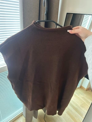 Brun stickad väst - Mysig brun stickad väst med rund hals och ribbade kanter. Perfekt att bära över en skjorta eller t-shirt för en avslappnad men stilsäker look. Enkel och tidlös design som passar till många outfits.