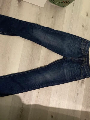 Levi's 511 mörkblå jeans - Säljer ett par klassiska Levi's 511 jeans i mörkblå tvätt. Modellen är slim fit/ men passar mer straight, med raka ben och snygga slitningar framtill. Tillverkade i bomull med en skön stretch. Perfekta för dig som gillar en tidlös och avslappnad stil.