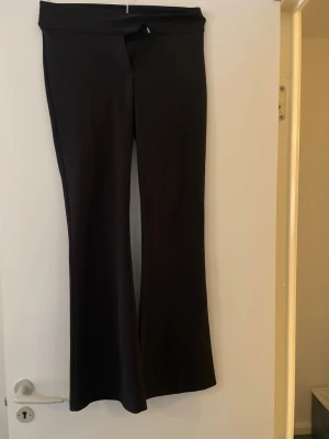 Svarta utsvängda byxor Gina Tricot - Säljer ett par svarta utsvängda byxor från Gina Tricot i storlek XS. Byxorna har hög midja och bred linning, tillverkade i ett stretchigt material som sitter snyggt. Perfekta för en trendig och bekväm look.