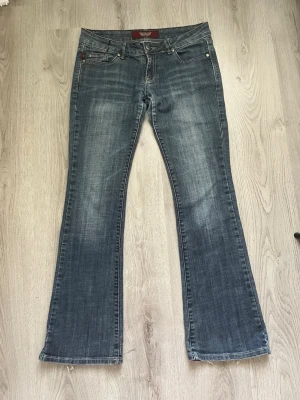 Lågmidjade jeans - Säljer ett par blå bootcut jeans från Rock & Republic med snygg slitning.