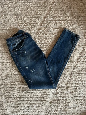 Dondup George jeans - Säljer just nu dessa otroligt feta Dondup George jeans i nyaste årsmodellen i en riktig fin blå färg med unika slitningar. Jeansen är i storlek 30. Midja 38cm. Lår 25cm. Ytterlängd 103cm. Innerlängd 80cm. Skicket på dessa är 9/10 inga skador eller defekter. För fler frågor eller funderingar är det bara att höra av sig. 