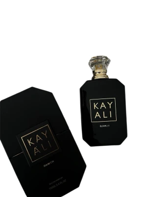Kayali Elixir | 11 Eau de Parfum limited edition  - Kayali Elixir 11 är en lyxig parfym i en svart, elegant flaska med gulddetaljer och en kristalliknande kork. Doften har noter av rött äpple, ros, jasmin, vanilj och patchouli. Förpackningen är också svart med guldtext och har en modern, geometrisk form. Finns ej att köpa online längre!!! Helt ny och nypris var runt 1800kr